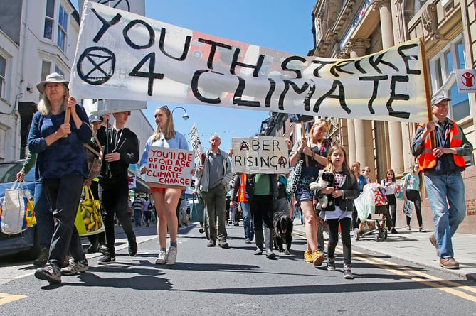 AB2706 CLIMATE97 PHOTO CODE 19DPJ27JUN97 - PHOTO DAVID ARWYN PARRY JONES / CAMBRIAN NEWS PRESS PHOTOGRAPHER - 27JUNE2019 - REF Chris; YOUTH STRIKE 4 CLIMATE ABERYSTWYTH 21 JUNE - Protest against climate change march in Aberystwyth last Friday. - Itinerary - All school children will have gathered in front of the train station by 12pm and we will stay here for 15/20 minutes to shout, chant and chalk the pavements. This is a good spot to meet us if you are coming from anywhere else as its right by the bus and train station. - Walk towards Rummers bar, then turn right up the road towards the clock tower. - Everyone will have arrived at the clock tower where we will gather for roughly 15 minutes to chant, chalk and cover the street in posters highlighting the climate issue. - We will walk down the street and we will stop at the bottom of the road by Barclays to stage a short die-in on the pavement. A die-in is when everyone lies down on the floor silently pretending to be dead, this looks very dramatic and effective! We might also be supported outside Barclays by a peaceful Buddhist group (still being planned) - Then we will jump up again and continue to chant and march all the way down to the Morrisonâs round about where we will walk around the roundabout. - And then lastly we will walk to the council buildings where we will stay for the rest of the day until 3pm with all sorts going on including: Â· Face painting Â· Poster &sticker making Â· Seed bombing . Chalking Â· Food will be provided Â· Peoples assembly Â· Aerial hoop performers Â· Possibility of George Monbiot doing a talk (still being arranged but fingers crossed) Â· Litter picking Â· Lots of shouting, chanting, dancing, sitting, eating, laughing (etc)Regards, Youth Strike 4 Climate Aberystwyth. - PHOTO - Protesters