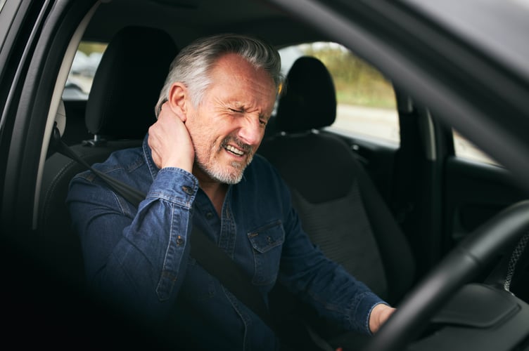 Senior man inside car after road traffic accident in pain suffering with whiplash injury