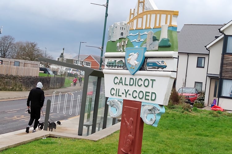 A welcome sign in Caldicot denoting its proximity to the Severn Bridge which is depicted along with the castle and railway line. 